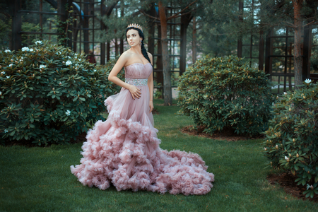 The Queen in a magnificent pink dress is walking in the garden among the trees.の写真素材
