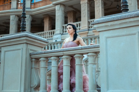 Girl with a crown on his head standing on the balcony of the castle.の写真素材