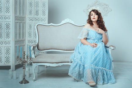 Beautiful woman with overweight sitting on the sofa in the room.の写真素材