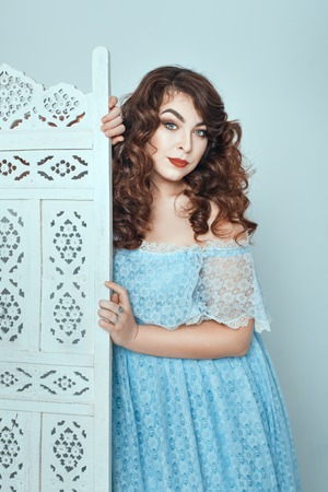 Chubby brunette woman in a dress looks from behind the screen.の写真素材