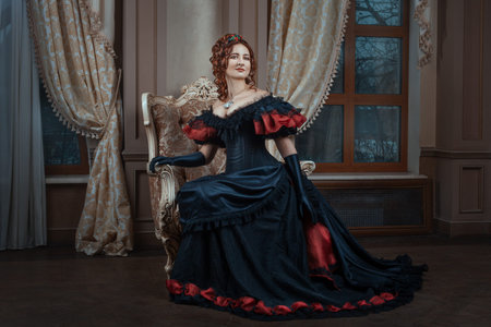 Woman in Victorian dress sitting on a chair in the room.