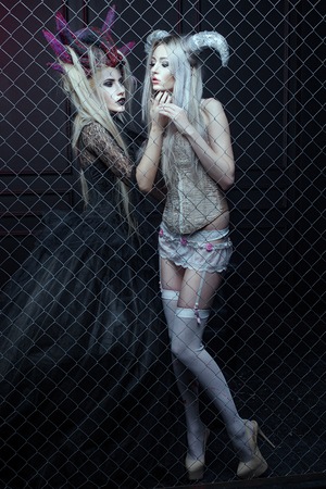 Two women in Gothic dresses are closed in a cage. They carry on the horn head.の写真素材