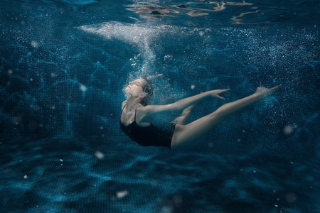 Woman dancing under the water around the air bubbles.の写真素材
