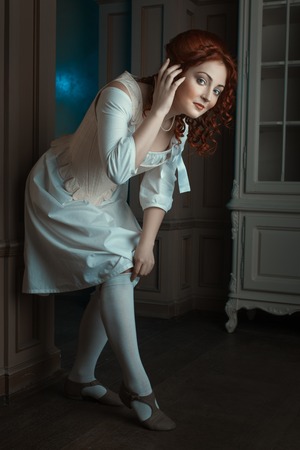 Girl flirtatiously straightens stockings on her feet, she was in the Renaissance style.の写真素材