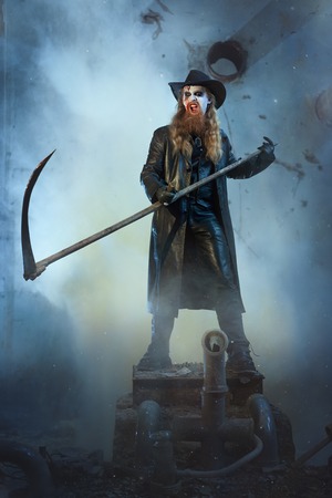 Horrible man brandishing a scythe and shouts.の写真素材