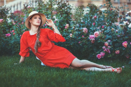 Woman lies on the grass among the flowers, she is dressed in a red short dress.の写真素材