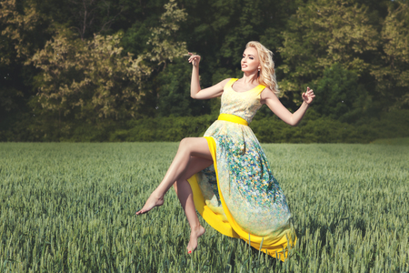 Blond woman levitating over the field on a sunny day.の写真素材