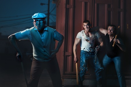 Old man goes through the city at night, behind him two criminals.の写真素材