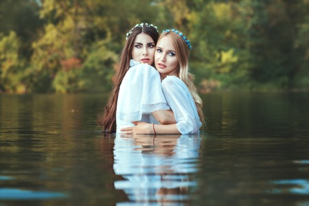 Women lesbian embrace standing in water in the lake.の写真素材