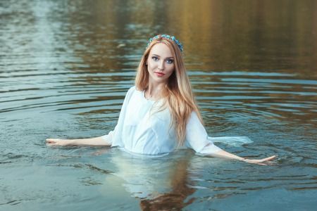 Woman in a white dress, she stands in the water in the lake.の写真素材