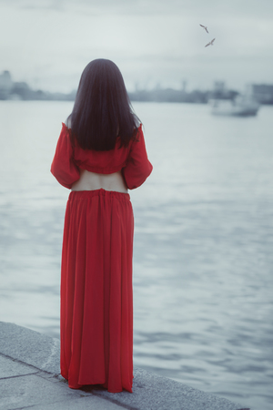 Woman stands on the shore of the sea and waiting.の写真素材