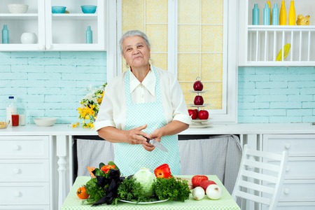 Grandmother in an apron the vegetarian, she cooks food from vegetable products.の写真素材
