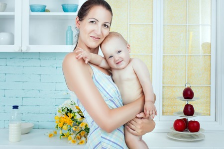 Mother holds a baby child, they smile.の写真素材