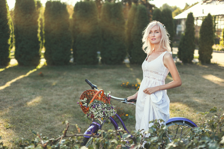 Woman with a bicycle walks through the park on a sunny day.の写真素材