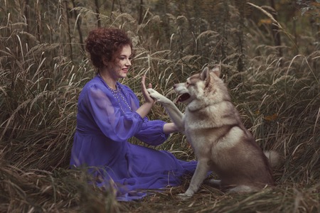 Dog put a paw on a hand to the girl, they are friends.の写真素材
