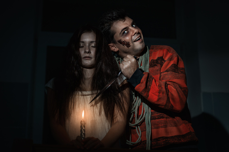 Creepy man and woman are standing in the room, he had a knife and weighs a rope around his neck.の写真素材