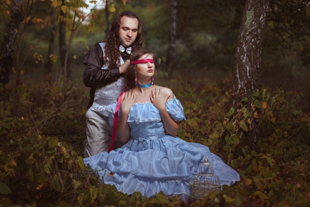 The man closed a red tape eyes to the woman, they flirt in the wood.の写真素材