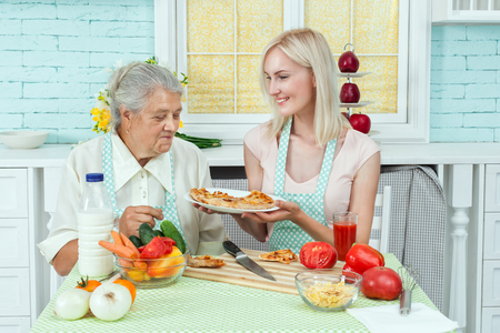 Girl cook a pizza in the kitchen, she offers her mom eat.の写真素材