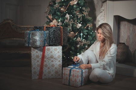 Girl unpacks gifts under the Christmas tree.の写真素材