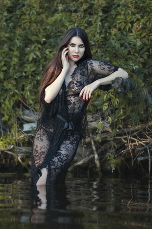 Sexy woman dressed in a negligee standing in the water.の写真素材