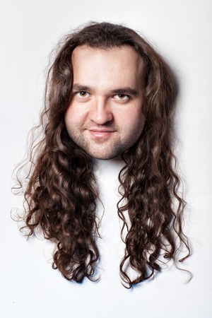 Funny men's head, hair with long curly hair. Close-up on a white background head.の写真素材