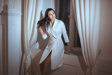 Woman in a dressing gown at the window in the evening.の写真素材