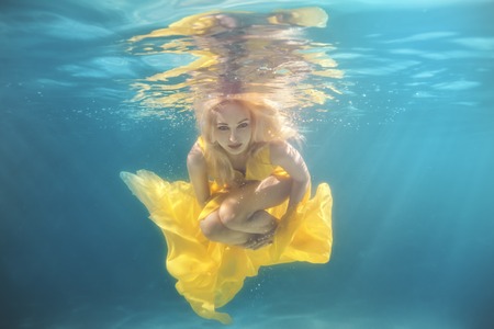 In the pool underwater swim woman, she in a yellow dress.の写真素材