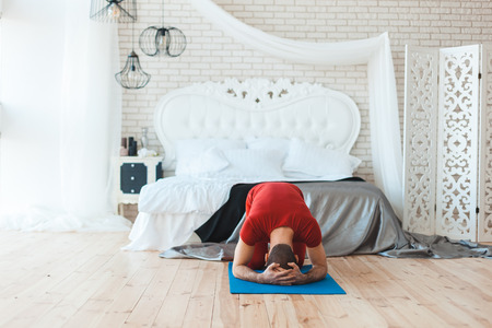 Man meditates with his head on the floor, he is in the bedroom.の写真素材
