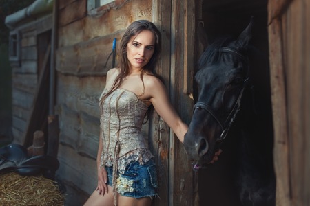 Woman and horse in a wooden shed in rural areas.の写真素材