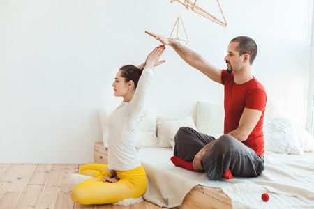 Young man and woman meditating yoga in the morning in a room on the bed.の写真素材