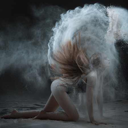 Woman shows a performance with flour. Her hair scatter the flour around the room.の写真素材