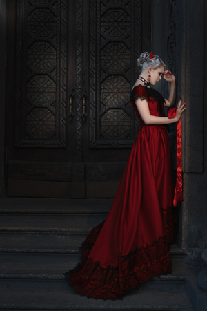 Sad woman in retro style on the steps of a fairytale castle.の写真素材