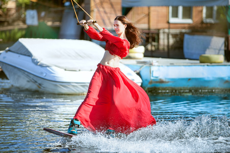 Woman in a red dress skates on a wakeboard.の写真素材