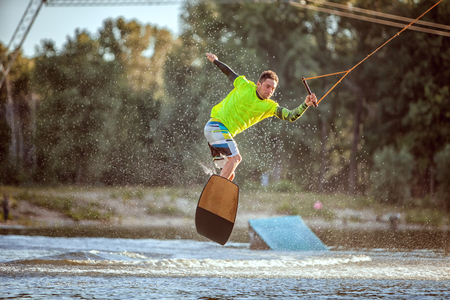 Athlete rolls and jumps on the board along the lake.の写真素材