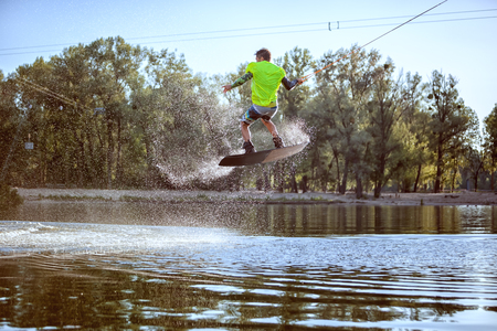 Man is engaged in extreme sports, he jumps on the board on the water.の写真素材