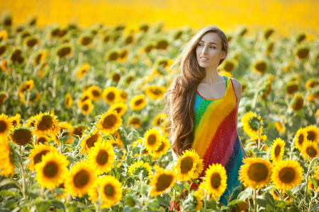 Young woman is standing in a field among sunflowers.の写真素材