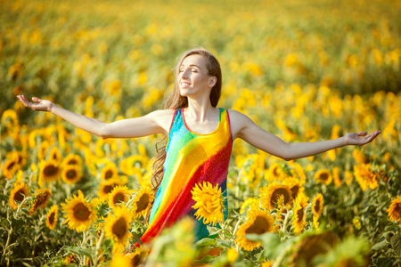 Woman smiles happily in the field standing among the blooming sunflowers.の写真素材