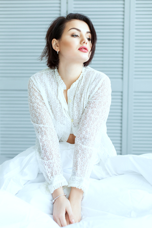 Beautiful woman sitting in bed in the early morning.の写真素材
