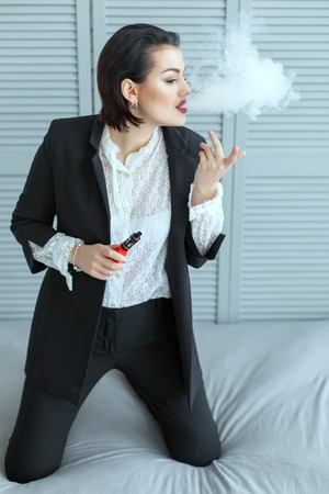 Cute woman smoking e-cigarette with smoke in the room.の写真素材