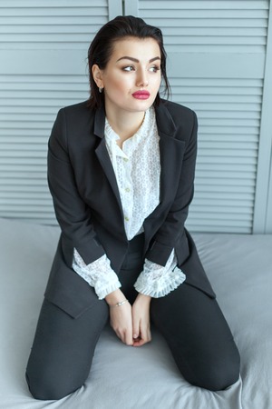 Pretty woman with a sad face, she kneels in bed and dreams.の写真素材