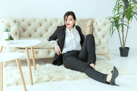 Beautiful woman in a business suit sitting on the floor, she misses.