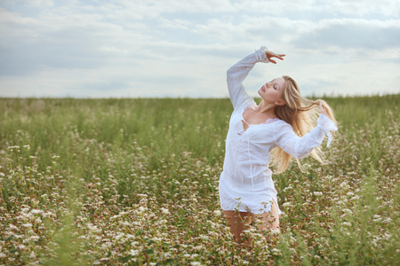Woman stands in the field and enjoys nature.の写真素材