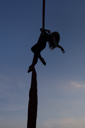 Aerial yoga on a sky background silhouette of a woman.の写真素材