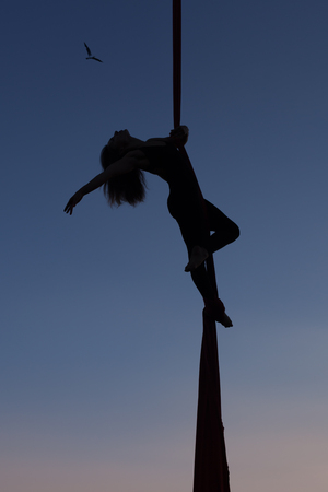 Woman is showing gymnastics in the air on a hammock.の写真素材
