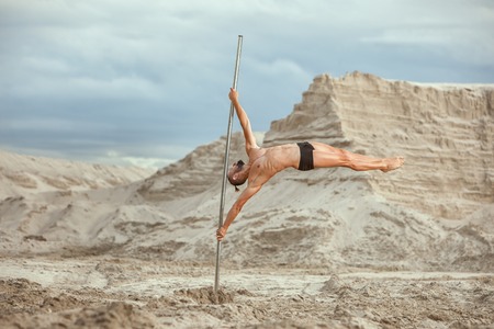 Athlete acrobat.Male Athlete acrobat doing acrobatic stunts on the pole.の写真素材