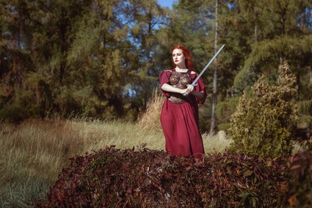 In the forest, a woman with a sword, she is a warrior and ready to defend.の写真素材
