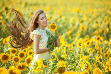 Woman gets a relaxation in a field with yellow sunflowers.の写真素材