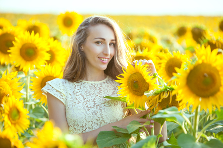Lovely woman in a field of sunflowers, close-up portrait.の写真素材