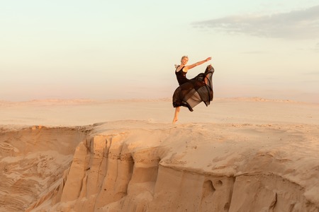 Dancer jumped while dancing, she was in the desert of their sand.の写真素材