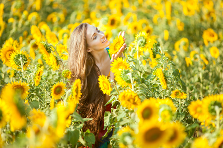 Happy woman on a flower field enjoys herself.の写真素材